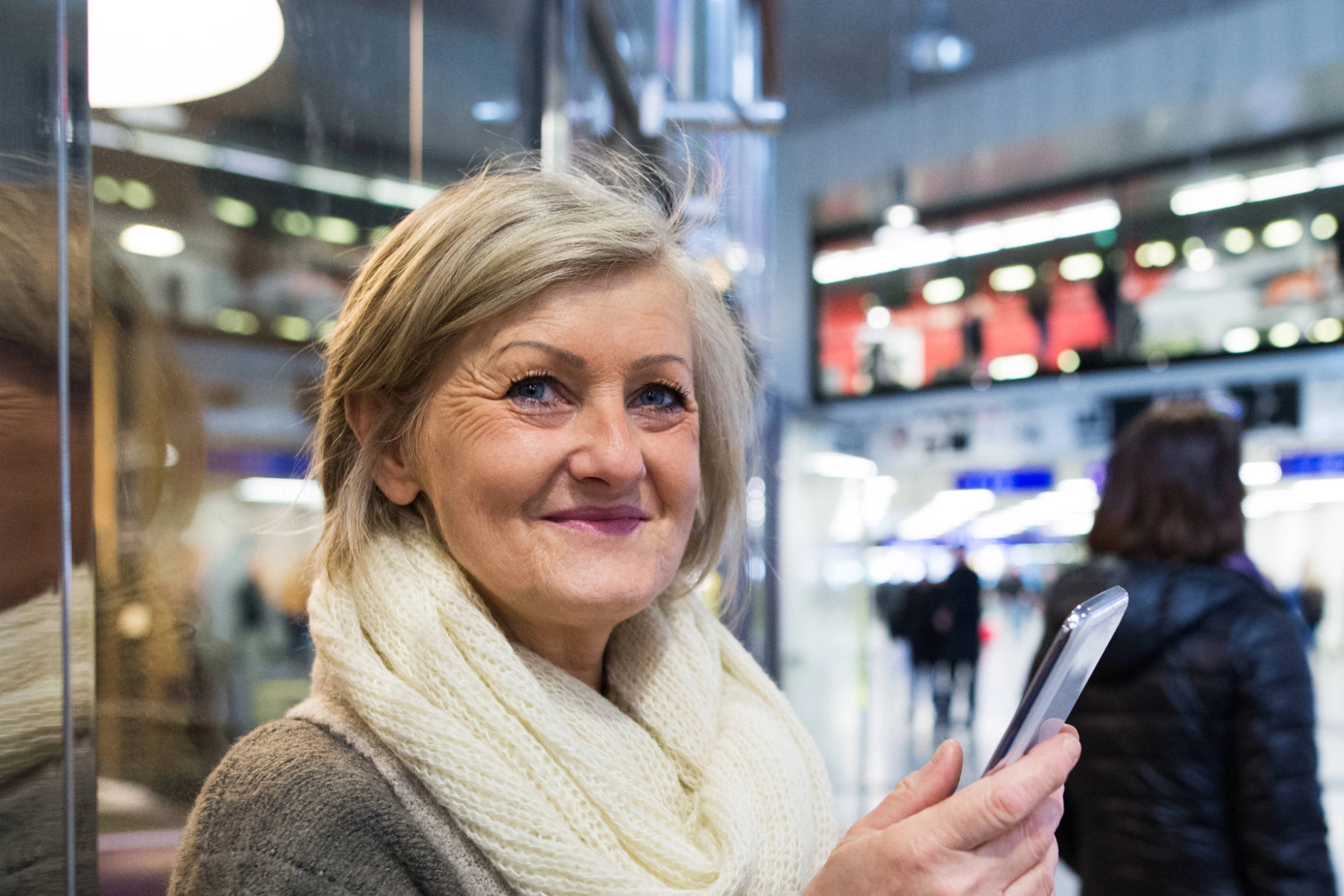 Eine ältere Frau mit einem Smartphone in der Hand.